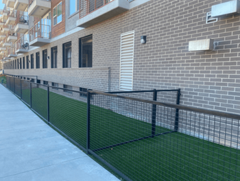a building with a grassy area and a fence in front of it